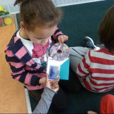 Children in 2M comparing the size of a cassette tape and a cd rom